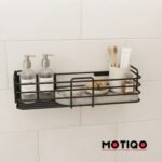 Black metal wall-mounted bathroom caddy holding pump bottles, toothbrushes, soap, and toiletries against a white tiled wall