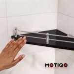 Black glass corner shelf with chrome guardrail mounted on tiled wall