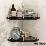 Two black glass corner bathroom shelves with chrome guardrails mounted on a white tile wall
