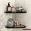 Two black glass corner bathroom shelves with chrome guardrails mounted on a white tile wall