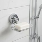 Chrome wall-mounted soap dish holding a bar of white soap on a tiled shower wall